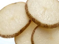 Fresh raw potato slices close-up showing natural starchy texture and skin, macro food photography for culinary, nutrition, and cooking content.