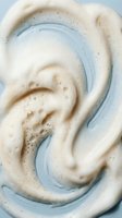 Creamy swirled foam texture with bubbles in soft beige and blue tones for skincare cosmetics and spa wellness backgrounds.
