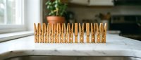 Row of wooden clothespins arranged on white marble counter in bright kitchen interior for laundry organization and household storage solutions.