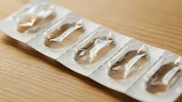 Clear gel capsules in blister pack on wooden surface for pharmaceutical and healthcare supplement packaging design applications.