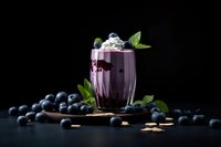 Fresh blueberry smoothie in glass with mint garnish surrounded by scattered berries on dark background for healthy lifestyle and nutrition concepts.