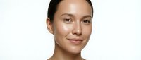 Young woman with East Asian ethnicity, natural makeup, and glowing skin against white background. Portrait suitable for beauty, skincare, wellness, and cosmetics marketing campaigns.