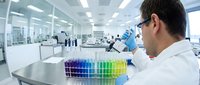 Male scientist in white lab coat using pipette with colorful test tubes in modern laboratory. Research, analysis, chemistry experiments in sterile clinical environment.