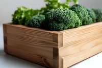 Fresh green broccoli florets in wooden box on white background. Close-up view of organic vegetables with selective focus highlighting natural texture.