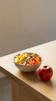 Healthy breakfast bowl with mixed fruits, granola, and yogurt on wooden table next to fresh apple for nutritious meal planning.