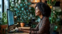 Young African American woman with natural hair working on computer with glowing zodiac and astrological symbols floating around screen in modern office setting.