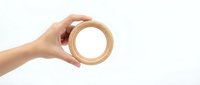 Female hand holding wooden ring on white background isolated for design projects and crafting concepts.