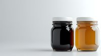 Glass jars filled with dark and amber liquid on white background, minimalist composition showing contrast between honey and coffee or syrup products.