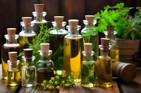 Assortment of essential oil bottles with cork stoppers surrounded by fresh herbs and flowers on wooden background for aromatherapy and natural wellness.