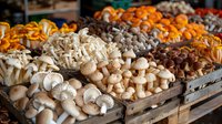 Fresh organic mushrooms and citrus fruits displayed at farmers market stall, variety of seasonal produce in wooden crates for healthy cooking and retail.