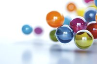 Colorful glass marbles scattered on white surface with selective focus on blue sphere, creating depth and bokeh effect for modern abstract composition.