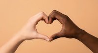 Two diverse hands forming heart shape symbol representing love unity friendship and togetherness against warm beige background for social campaigns.