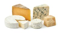 Assorted cheese varieties including cheddar, blue cheese, brie and aged blocks isolated on white background for food and culinary design projects.