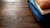 Folded soft towels in blue and beige tones on dark wooden background with copy space, minimalist bathroom decor concept for spa and wellness.