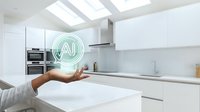 Modern smart kitchen with AI technology hologram floating above hand in bright white contemporary interior with skylights and minimalist design for future home automation.
