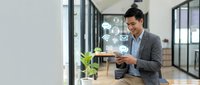 Man in business casual attire using tablet with digital icons for smart home automation, IoT connectivity, and wireless technology in modern office environment.