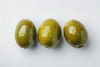 Three fresh green olives arranged in row on white background, showing natural texture and glossy surface. Isolated food photography for culinary use.