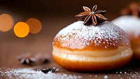 Sweet donut filled with vanilla cream, dusted with powdered sugar and decorated with star anise on dark background with bokeh lights and spice details.
