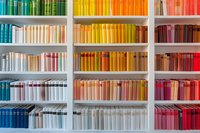 Colorful books arranged by spectrum colors on white shelves creating rainbow pattern, modern library organization system for interior design and decoration.
