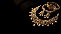 Elegant gold Indian bridal jewelry set with intricate necklace, bangles and earrings on dark background for luxury wedding fashion and traditional accessories.