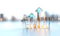 Glowing glass houses with upward arrows showing growth trend on light background with bokeh effect, representing real estate market or financial success.