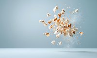 Flying popcorn kernels scattered in mid-air against light blue background, creating dynamic motion effect with shadows on white surface, food photography concept.