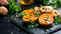 Grilled sweet peach halves garnished with fresh herbs and honey drizzle on dark slate board, rustic food styling for summer dessert or appetizer menu.