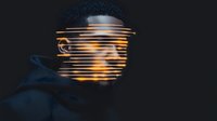 Young African American male portrait with glowing light strips effect across face on dark background creating futuristic cyberpunk aesthetic for creative projects.