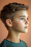 Profile portrait of young Caucasian boy with blue eyes and short brown hair wearing green t-shirt against peach background, soft lighting highlights facial features.