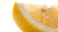 Fresh lemon slice macro shot showing juicy citrus texture and vibrant yellow color on white background for food and drink projects.