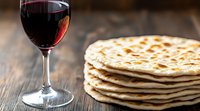 Stack of homemade flatbread with glass of red wine on rustic wooden table. Traditional Mediterranean cuisine photographed with selective focus.