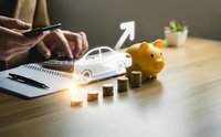 Car loan financing concept with piggy bank, coins, calculator and smartphone on wooden desk showing financial planning for auto purchase.