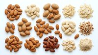 Assorted nuts and seeds collection arranged in circular piles on white background including almonds cashews walnuts pine nuts for healthy snacking.