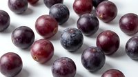 Fresh ripe plums scattered on white background, purple and red stone fruits for healthy eating, cooking ingredients, organic produce market display.
