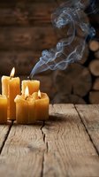 Lit yellow candles with flowing smoke on rustic wooden surface against blurred brick background, suitable for wellness, spirituality, and home decor design projects.