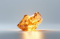 Glowing amber crystal formation on reflective surface with warm golden light illumination against neutral gray background, creating ethereal atmosphere.
