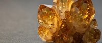 Rough golden amber crystals clustered together on neutral surface, showcasing natural mineral texture and warm translucent tones for geology, jewelry design, and educational materials.