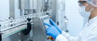 Pharmaceutical scientist in protective gear operating modern laboratory equipment for drug development and quality control in sterile manufacturing facility.