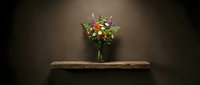 Vibrant mixed flower bouquet in glass vase on rustic wooden shelf against dark brown wall, elegant floral arrangement for home decor and interior design.