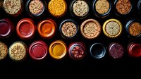 Colorful array of glass jars filled with diverse spices and seasonings viewed from above on dark background, showcasing vibrant cooking ingredients and culinary variety.