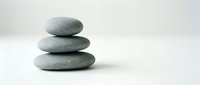 Three smooth gray zen stones stacked in balanced tower on white surface for meditation wellness spa relaxation mindfulness balance harmony concepts.