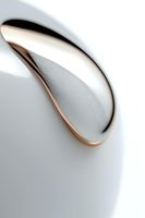 Minimalist close-up of white ceramic cup rim with condensation droplets against light background, featuring elegant curved design and copper-toned edge detail.