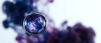 Crystal sphere reflecting cosmic nebula colors against blurred purple and blue smoke background for meditation and spiritual design projects.