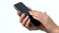 Close-up of female hands with manicured nails holding black smartphone with blank screen, isolated on white background for app mockup and technology design projects.