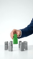 Businessman in navy suit selecting green wooden block among gray blocks, representing choice, differentiation, and recruitment strategy for corporate hiring and talent management concepts.