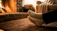 Cozy feet in warm knitted socks by crackling fireplace. Relaxing winter evening at home with soft lighting and comfortable atmosphere for hygge lifestyle.