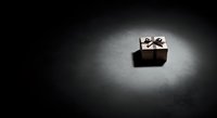 Black gift box with white ribbon bow isolated on dark background, suitable for holiday, celebration, and promotional design projects.