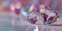 Crystal heart gemstones with faceted cuts reflecting pink and purple light on blurred romantic background. Perfect for Valentine's Day designs.