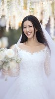 Happy Asian bride in white wedding dress and veil holding bouquet smiling outdoors on wedding day with soft natural lighting and bokeh background.
