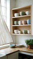 Wooden open shelving unit displaying stacked ceramic bowls in pastel colors, organized kitchen storage solution for dining and tableware display.